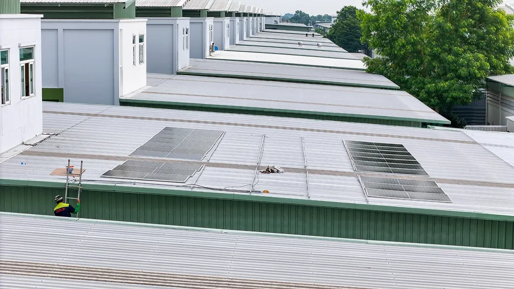 Aerial view of wide low-slope industrial roofs running across a manufacturing complex